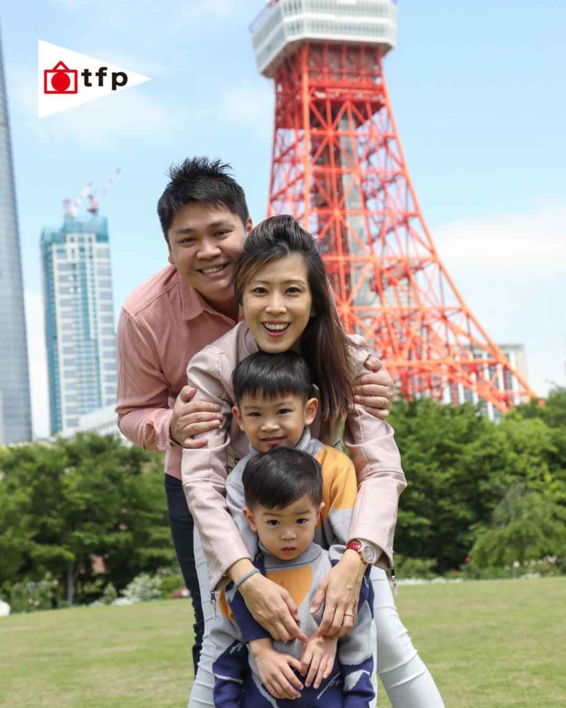 Family photoshoot at Zojo-ji Temple with Tokyo Tower in the background, parents and two young sons smiling naturally under the blue sky