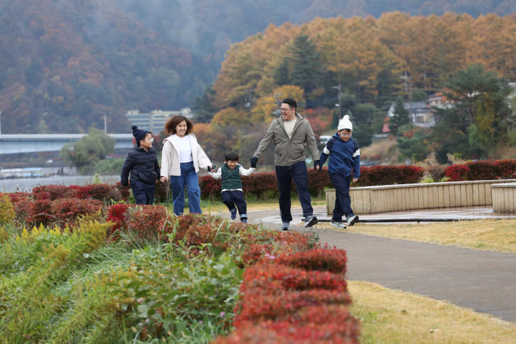 070 Family skipping together with autumn leaves in the background
