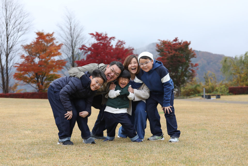096 Family standing together and smiling during playful moments in an autumn park