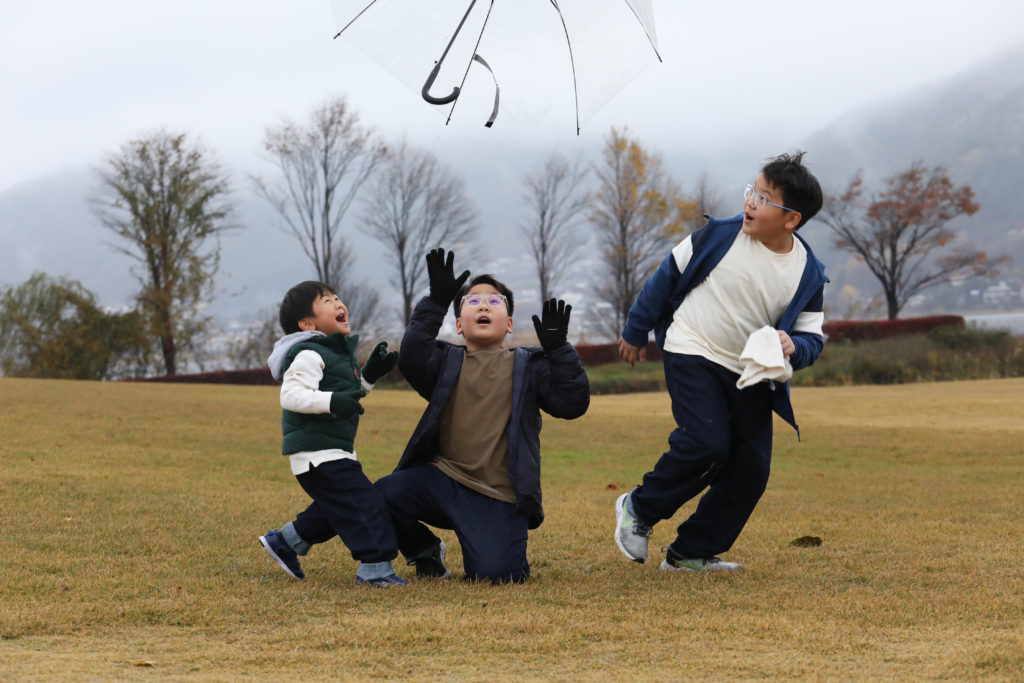 140 Three boys throwing and catching an umbrella in the park